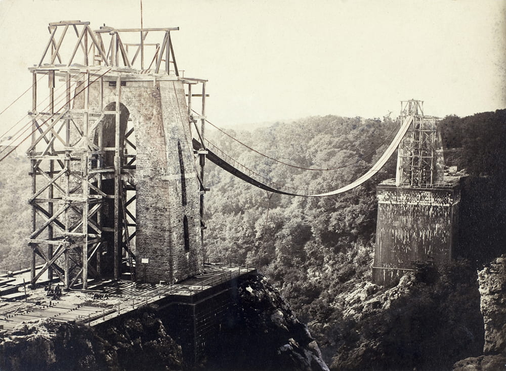 A view of Clifton Suspension Bridge, Bristol, from St Vincent’s Rocks, showing the piers under construction, along with chains, and scaffolding on the towers. DM216/3/4.